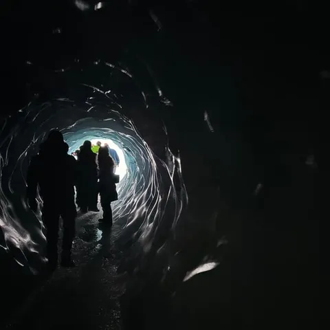 Figures silhouetted inside the Katla ice cave