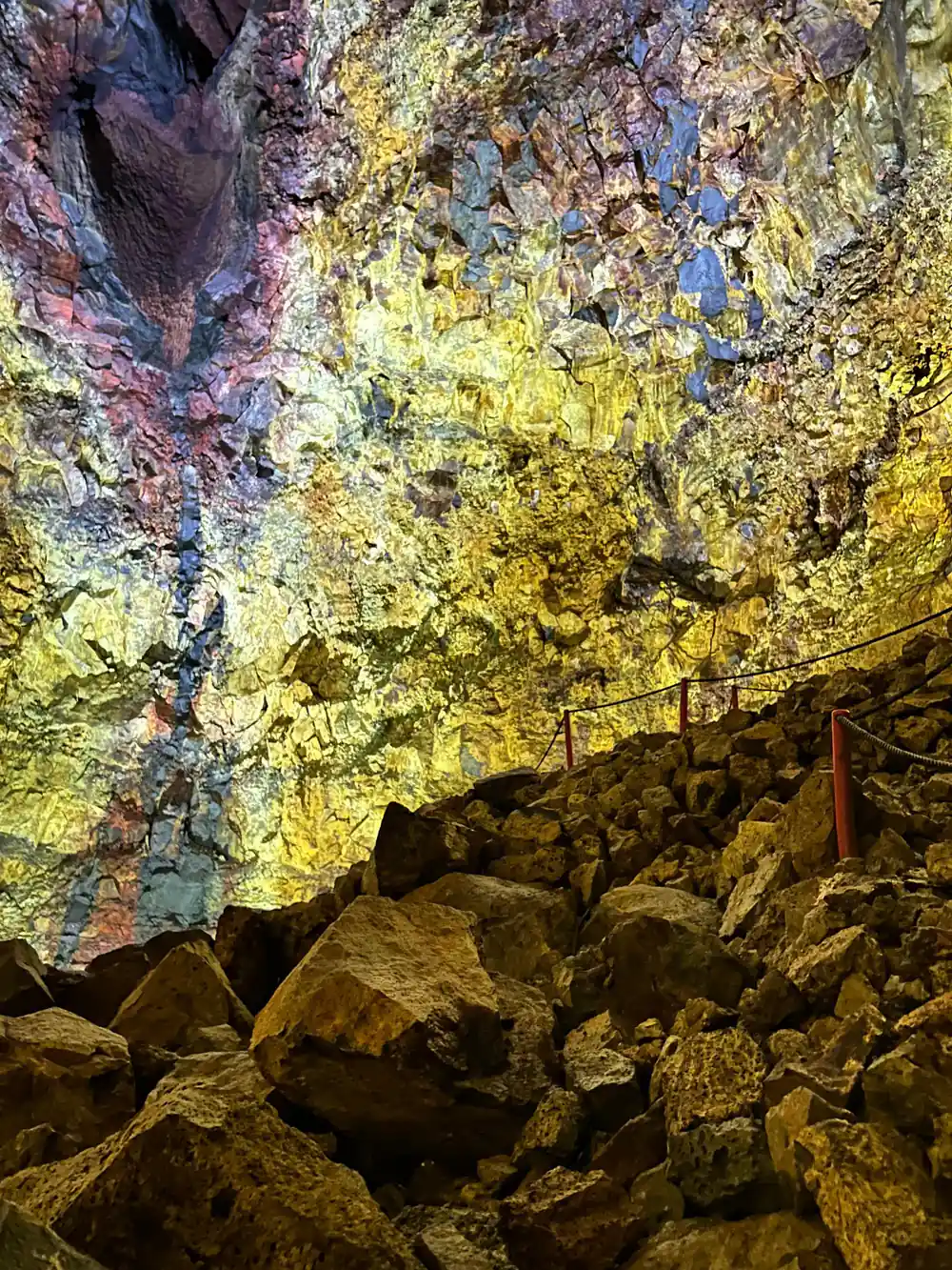 Boulders on the floor under a wall of yellow and blue-green