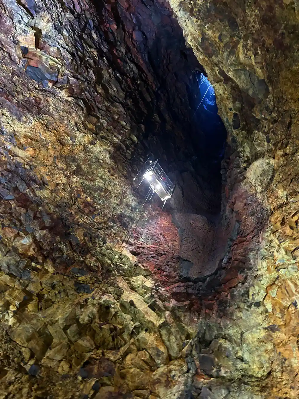 A lamp burning against the rock with the shaft dark above