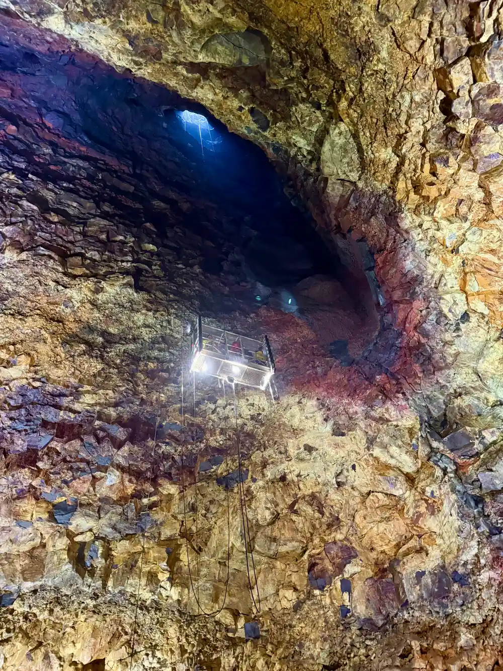 A lamp on the wall under a black opening in the rock