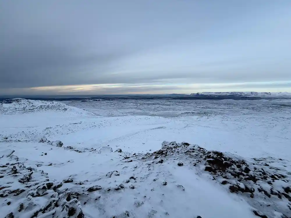 The lava plain under snow with a flat horizon beyond