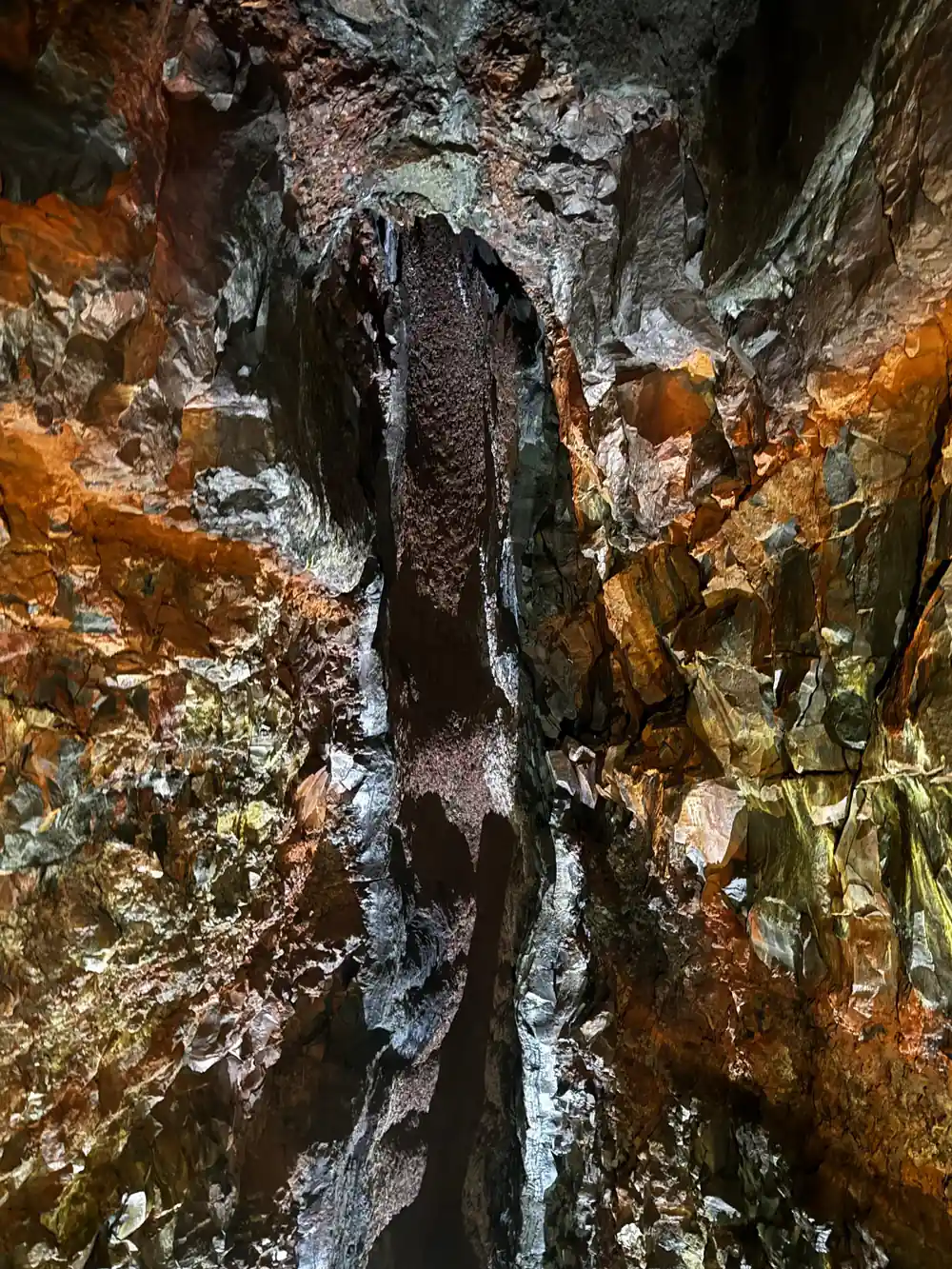 A pale mineral crust hanging on the rust-coloured wall